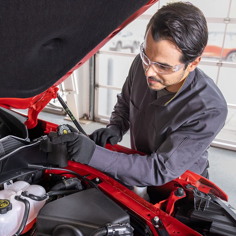 A service technician working on a red car